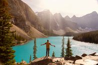 A Man Standing On The Cliff Over A Lake