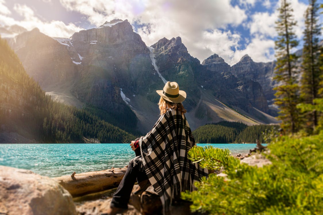 Free A Woman Sits On A Rock Beside The Lake Stock Photo