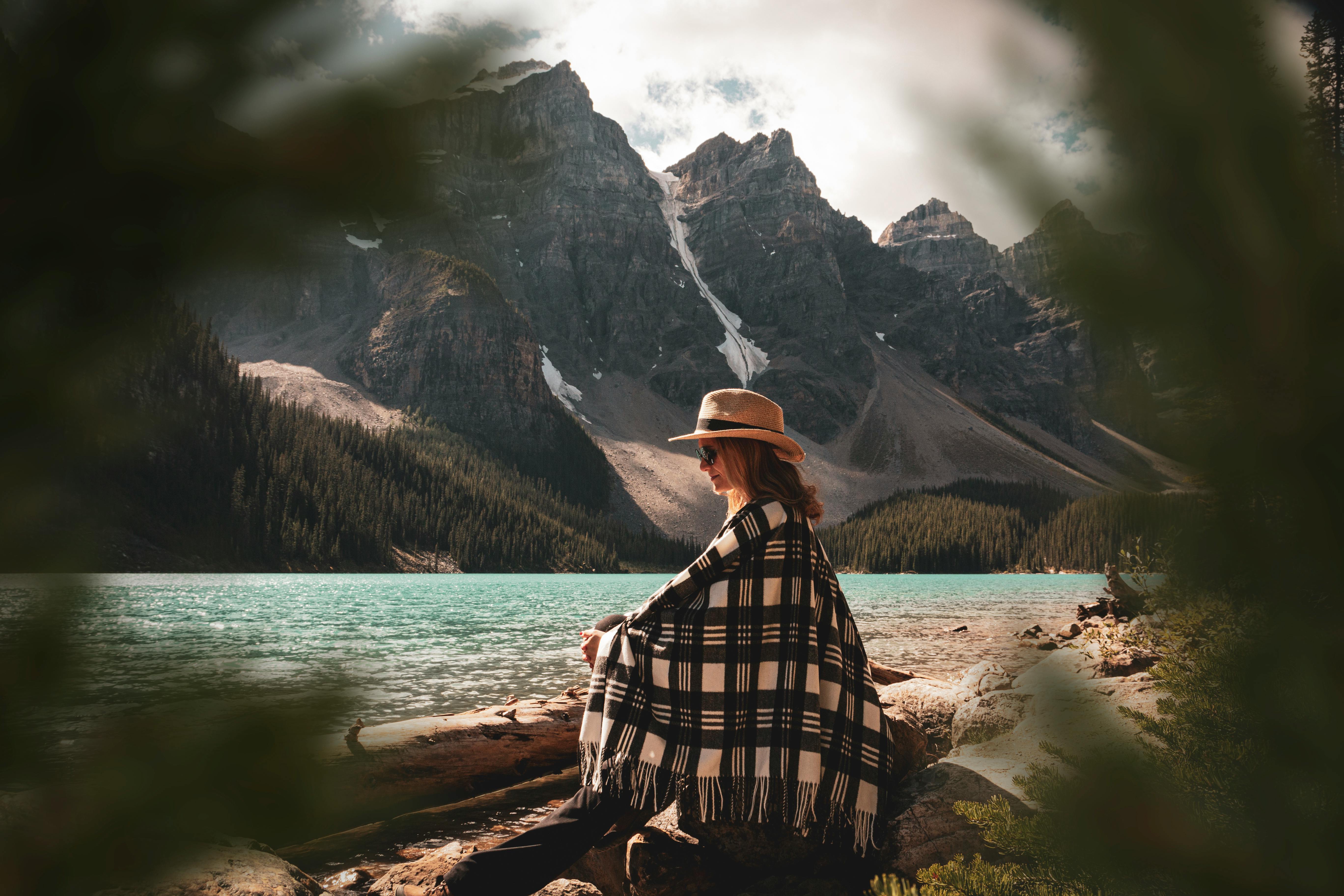 Woman enjoying a peaceful moment by Moraine Lake with scenic mountain views in Alberta, Canada.