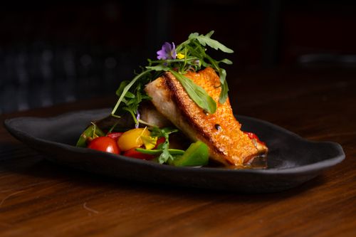 Free Delicious grilled salmon served with cherry tomatoes and greens on a stylish plate. Stock Photo