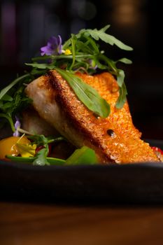 Deliciously seared fish fillet garnished with fresh greens, perfect for a culinary magazine.