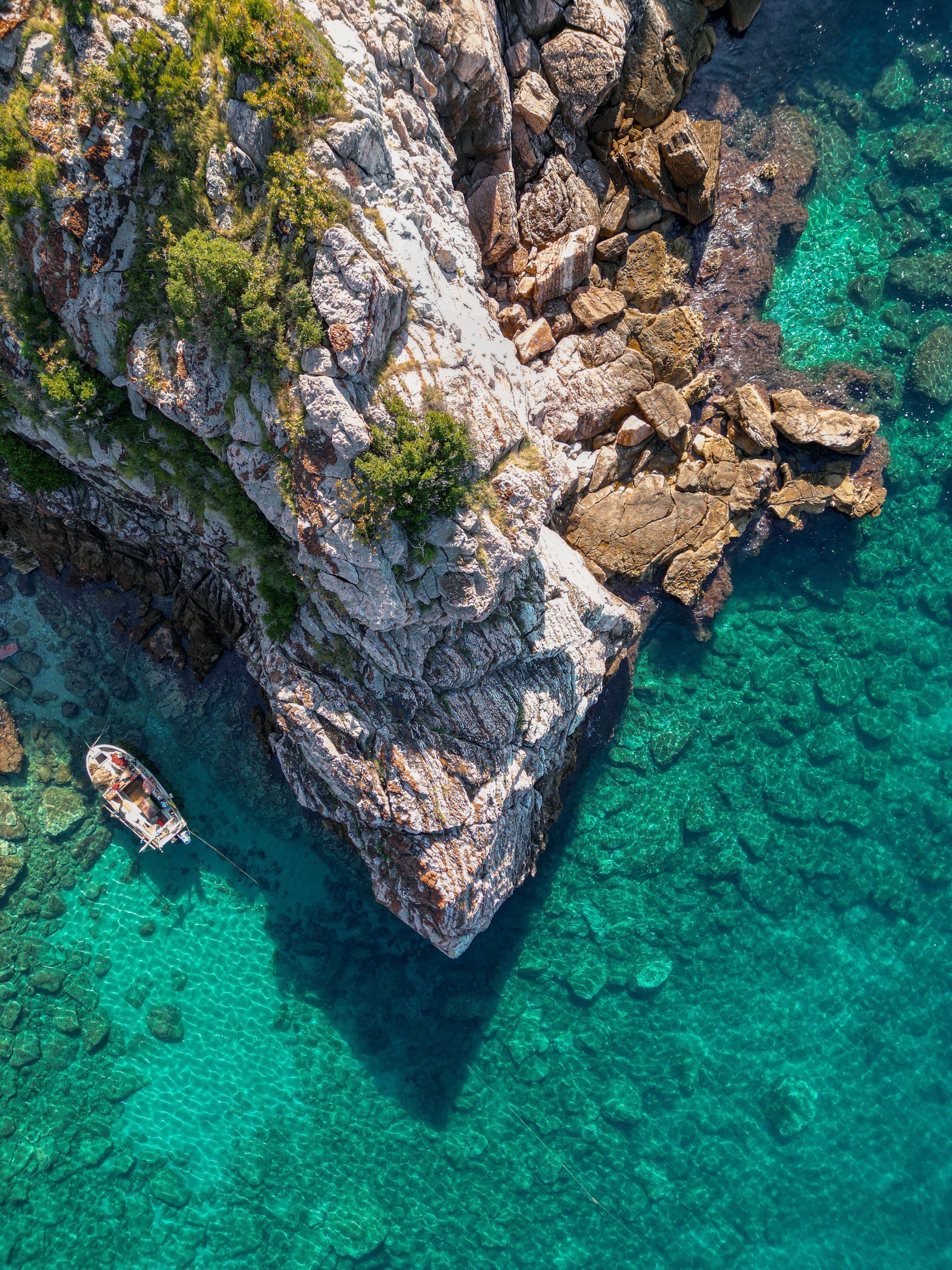 Aerial View of Boat and Rocky Coastline in Turquoise Waters · Free ...