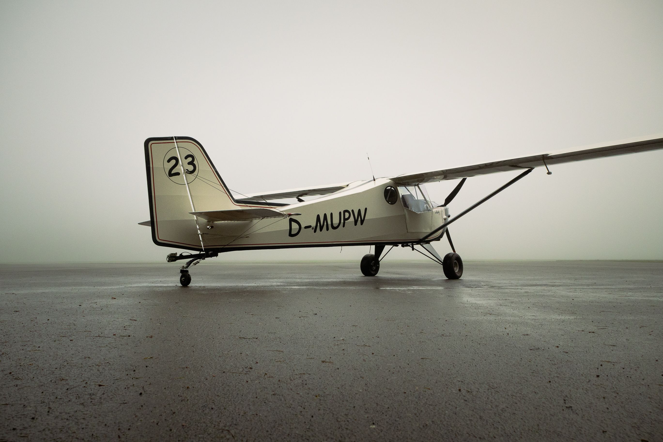 Vintage single-engine aircraft parked on a misty runway
