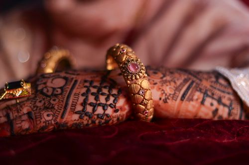 Free Close-up of beautiful mehndi art on hands adorned with traditional gold bangles. Stock Photo