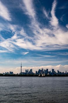 Scenic view of Toronto skyline featuring the CN Tower and a sailboat under a vibrant sky.