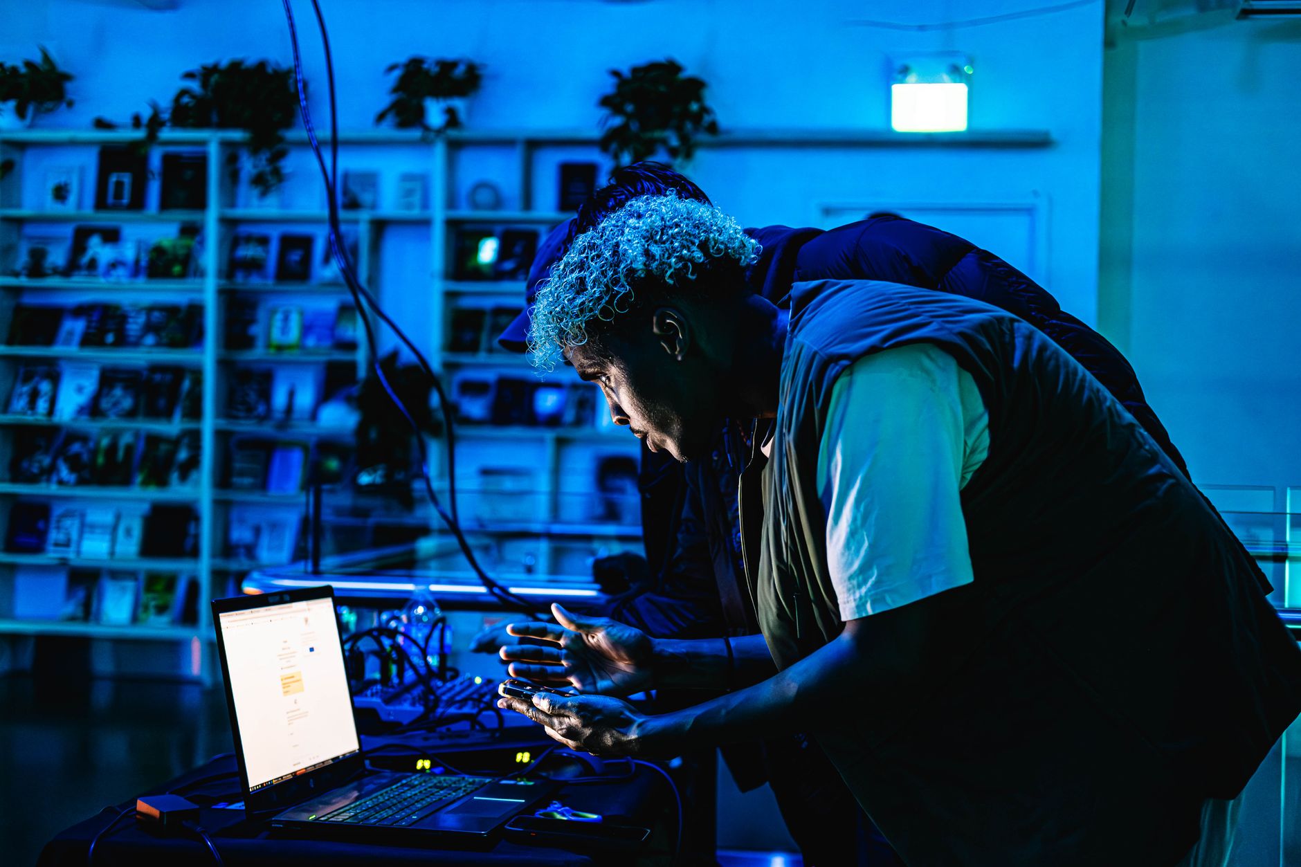 Person engaging with tech equipment surrounded by blue lighting, creating an artistic atmosphere.