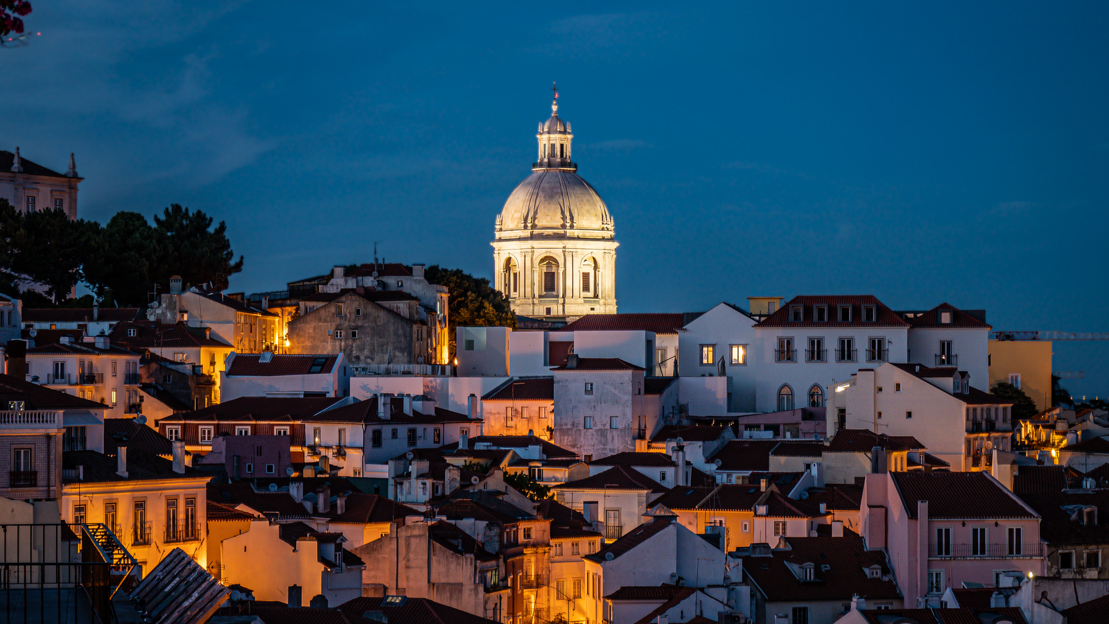 Lisbon after dark — the river, the bridge and the old city lit up.