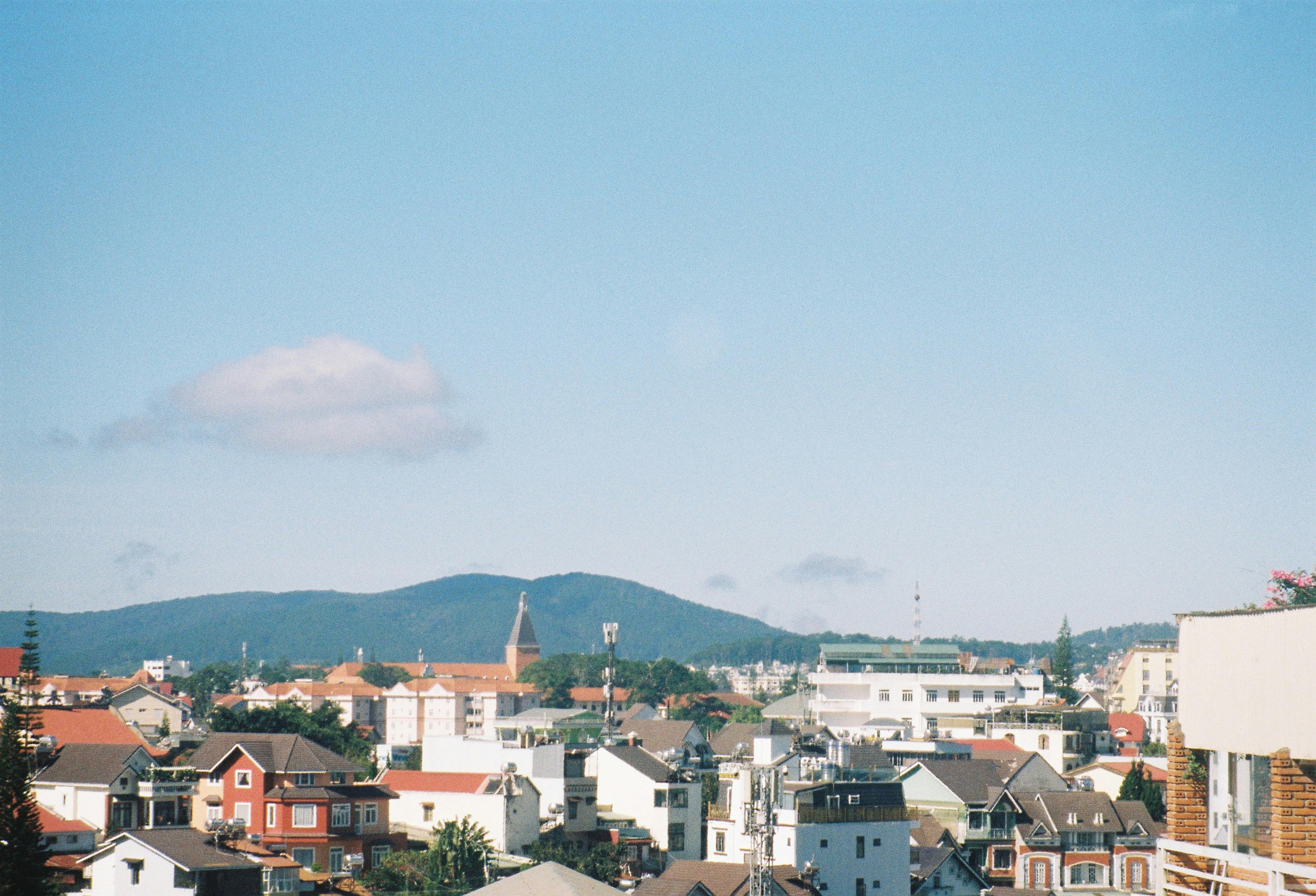 Charming cityscape with mountain backdrop and vibrant rooftops under clear blue sky.
