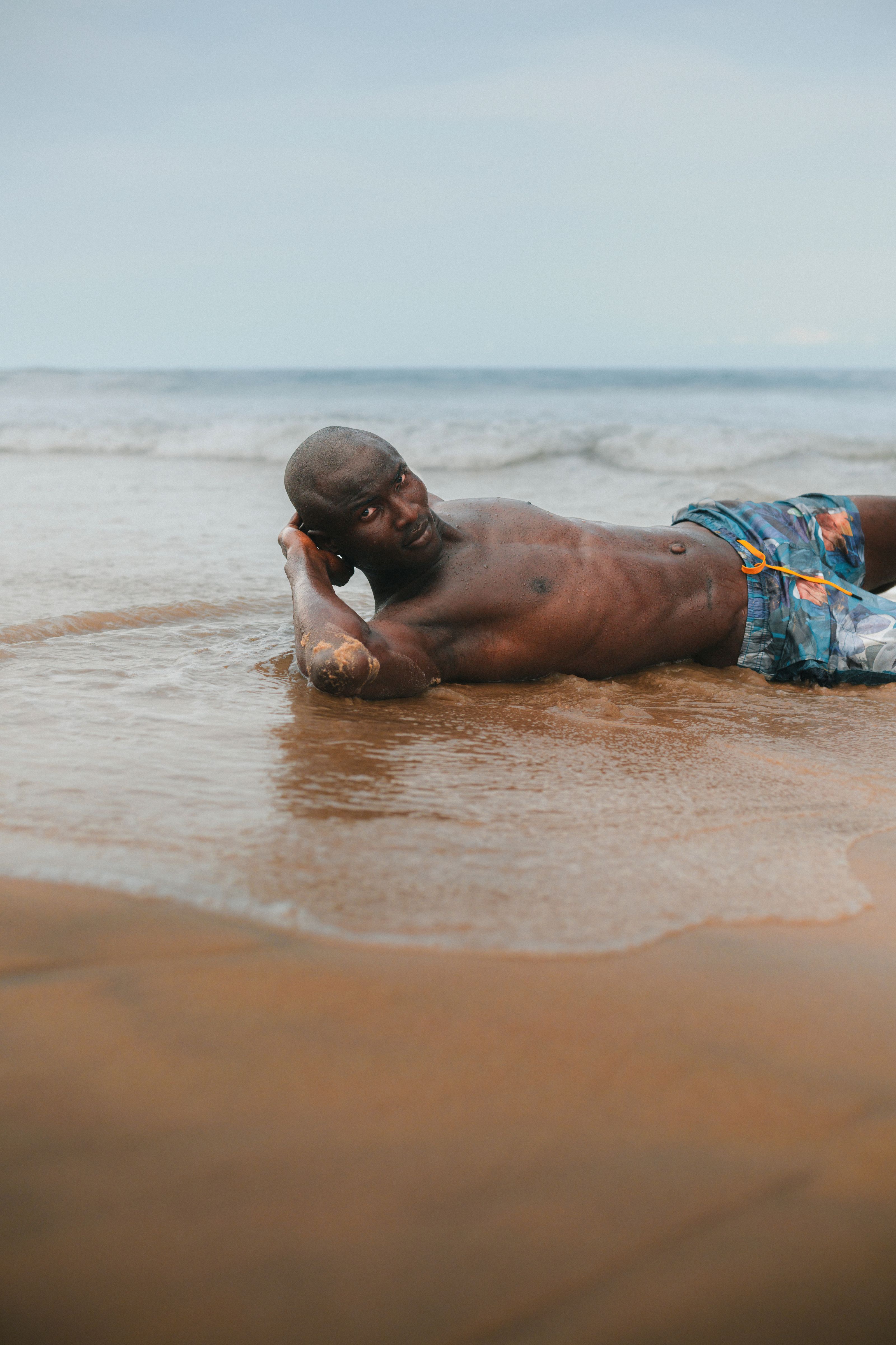 Um homem desfruta de um momento tranquilo em uma praia de areia em Abuja, Nigéria, com suaves ondas do oceano.
