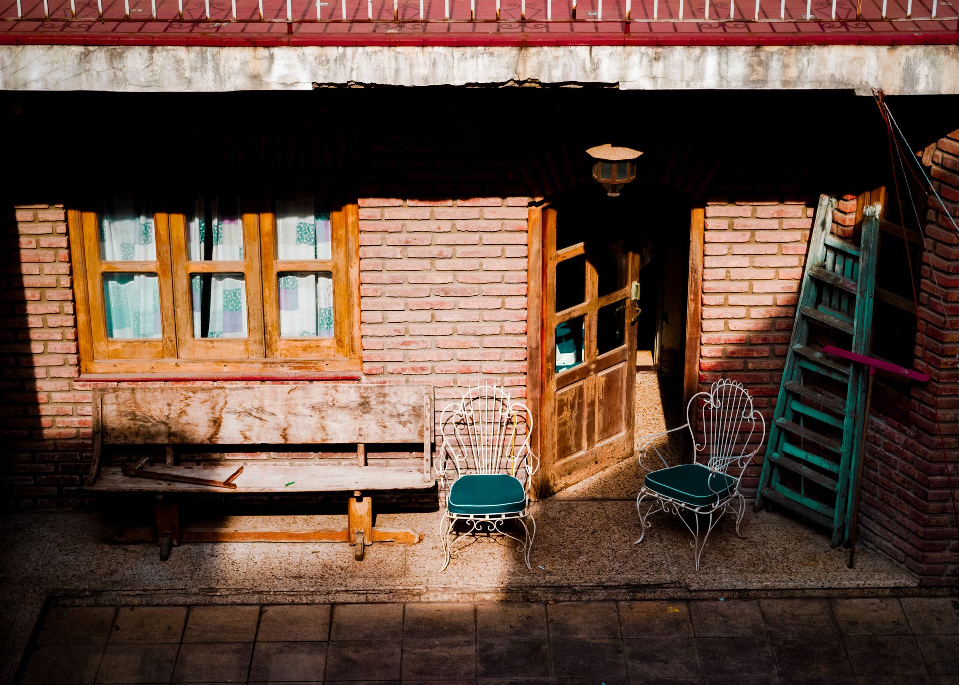 A quaint rustic patio with vintage chairs and wooden door in sunlight.