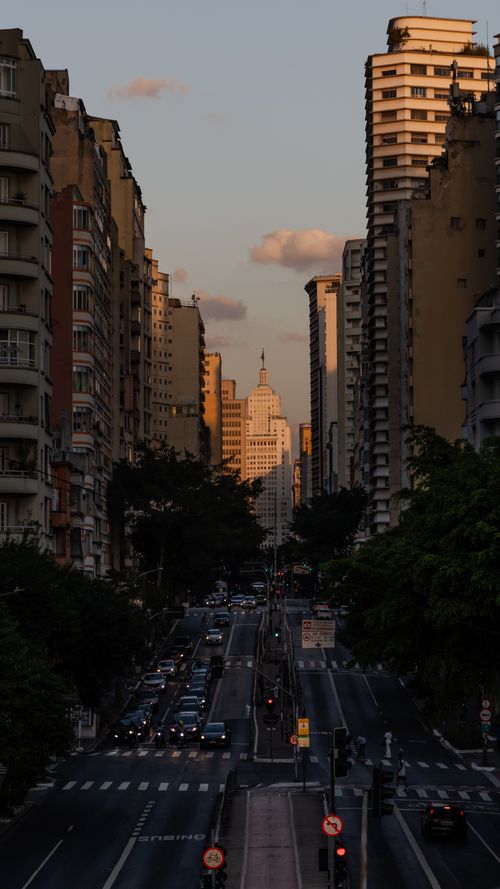 Free A bustling street in São Paulo at sunset, framed by high-rise buildings, capturing urban life. Stock Photo