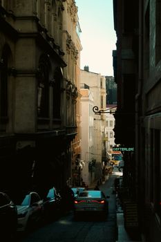 A picturesque view of a narrow street lined with historic buildings and cars in a European city.