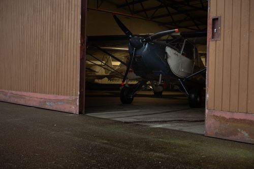 Free A vintage airplane partially visible through open hangar doors, capturing an industrial setting. Stock Photo