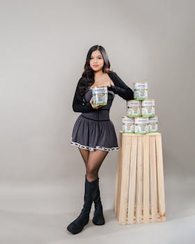 Model in a stylish outfit poses with skincare products in a studio setting.