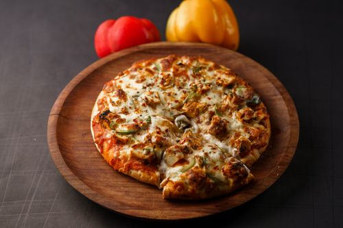 Free Tasty homemade pizza topped with veggies and cheese served on a wooden plate. Stock Photo