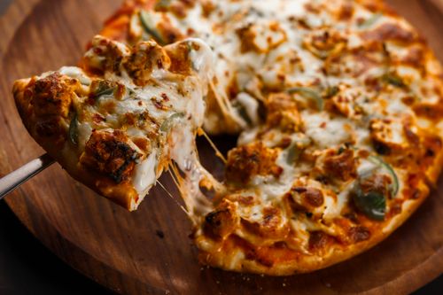 Free Mouth-watering pepperoni pizza slice with melted cheese on a wooden board. Stock Photo