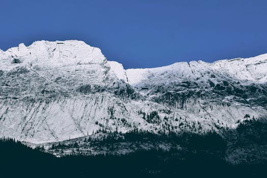 Majestic snowy mountain range under a bright blue sky, perfect for winter adventure enthusiasts.