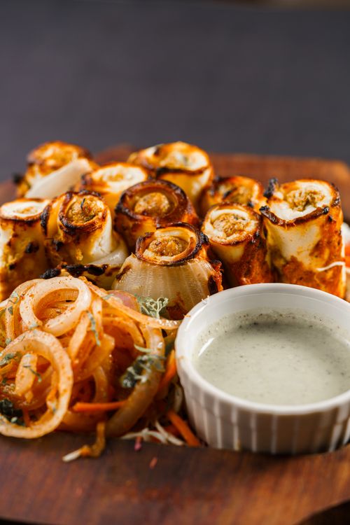 Free Grilled paneer and vegetable skewers with onion rings and chimichurri sauce on wooden board. Stock Photo