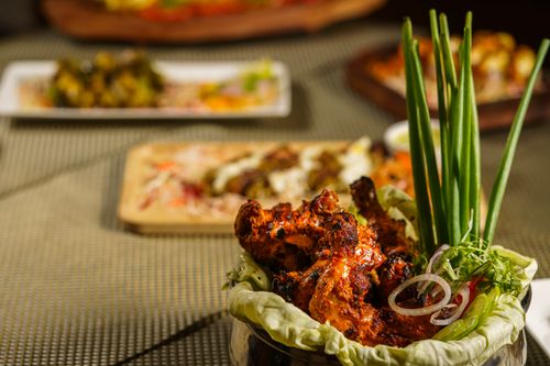 Free A close-up of spicy grilled tandoori chicken served with fresh garnishes. Stock Photo
