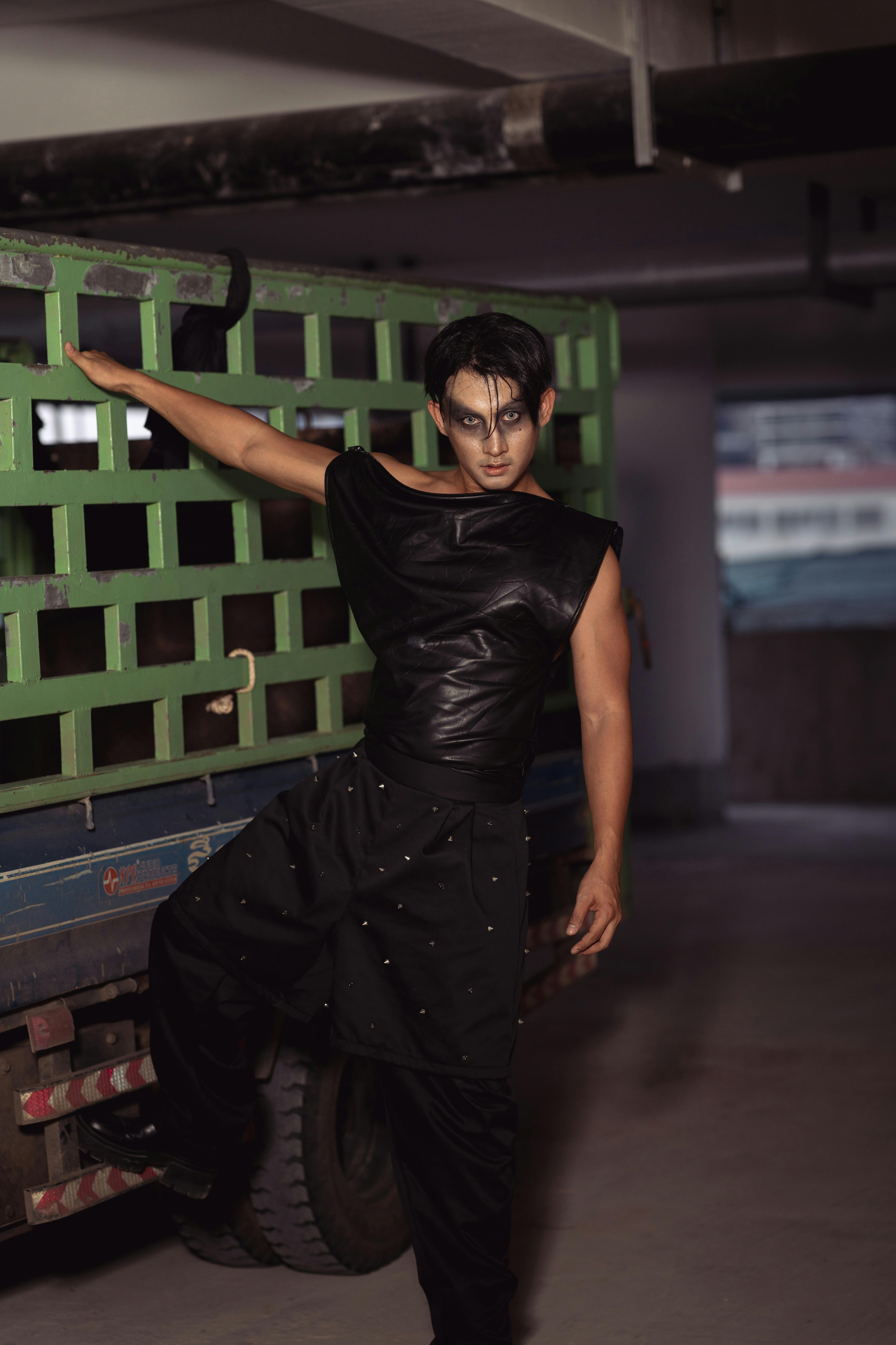 Gratis Model pria bergaya berpakaian hitam berpose dengan percaya diri di dekat truk. Foto Stok