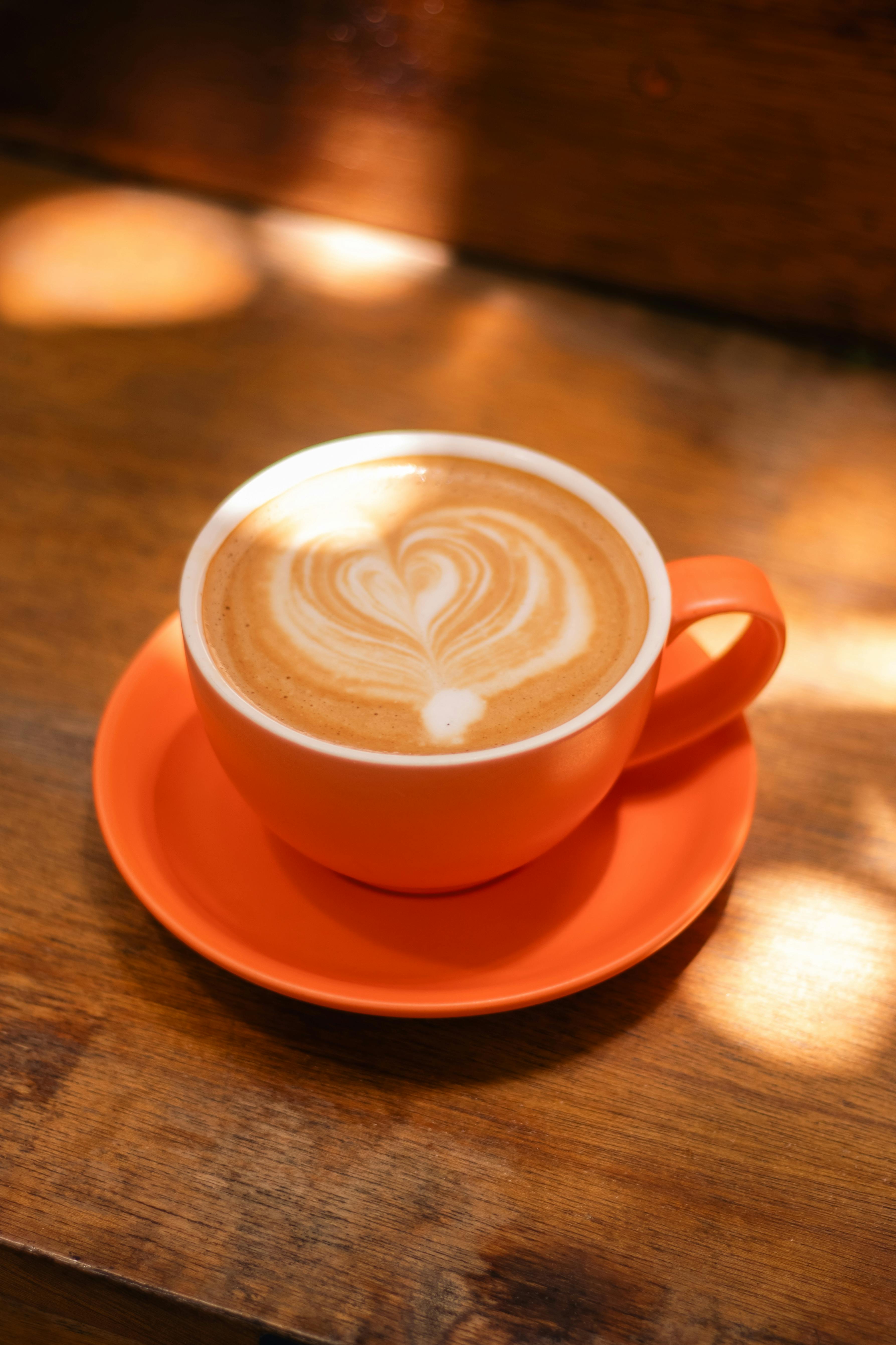 An inviting cup of coffee with heart-shaped latte art on a wooden table.
