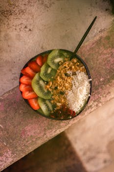 Colorful acai bowl topped with kiwi, strawberries, granola, and coconut, perfect for a healthy breakfast.