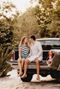 一对幸福的夫妇坐在卡车后挡板上，在户外享受夏日时光