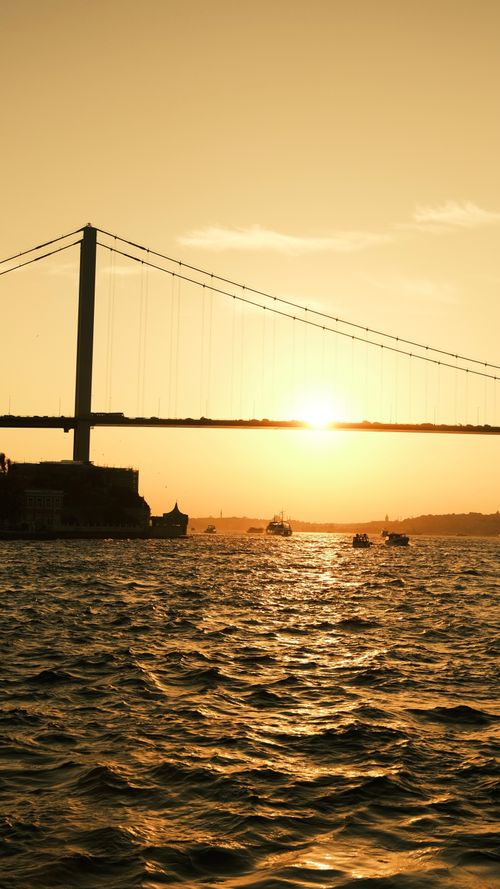 Free A stunning sunset view of the Bosphorus Bridge over calm waters in Istanbul. Stock Photo