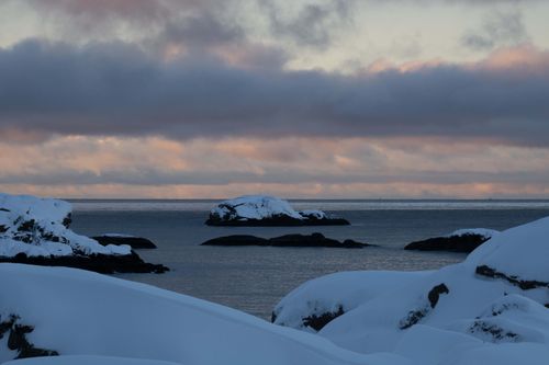 Free Serene winter coastal scene with snow-covered rocks and twilight sky. Stock Photo