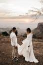 一对情侣身着婚纱，在日落时分的秀丽山景中共享浪漫时刻