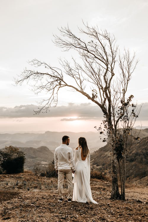 Free A Couple In White Dress Standing In View Of The Mountain Stock Photo