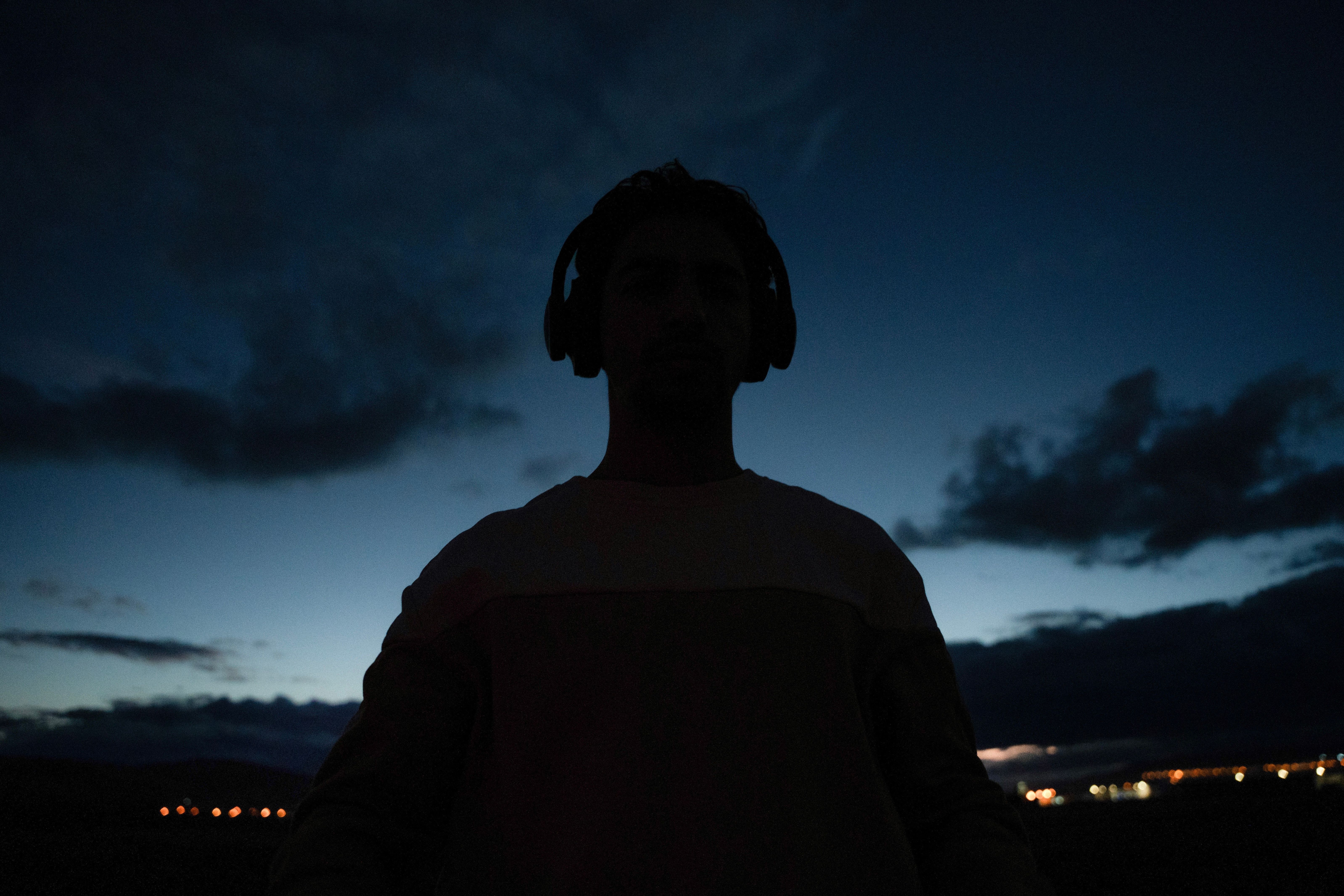 Silhouette of an individual wearing headphones against a twilight sky, capturing serene ambiance.