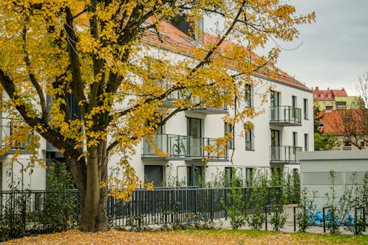 A modern apartment surrounded by vibrant autumn trees and yellow leaves.