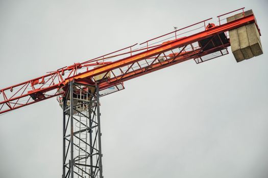 A striking red construction crane extending into a clear sky, symbolizing growth and development.