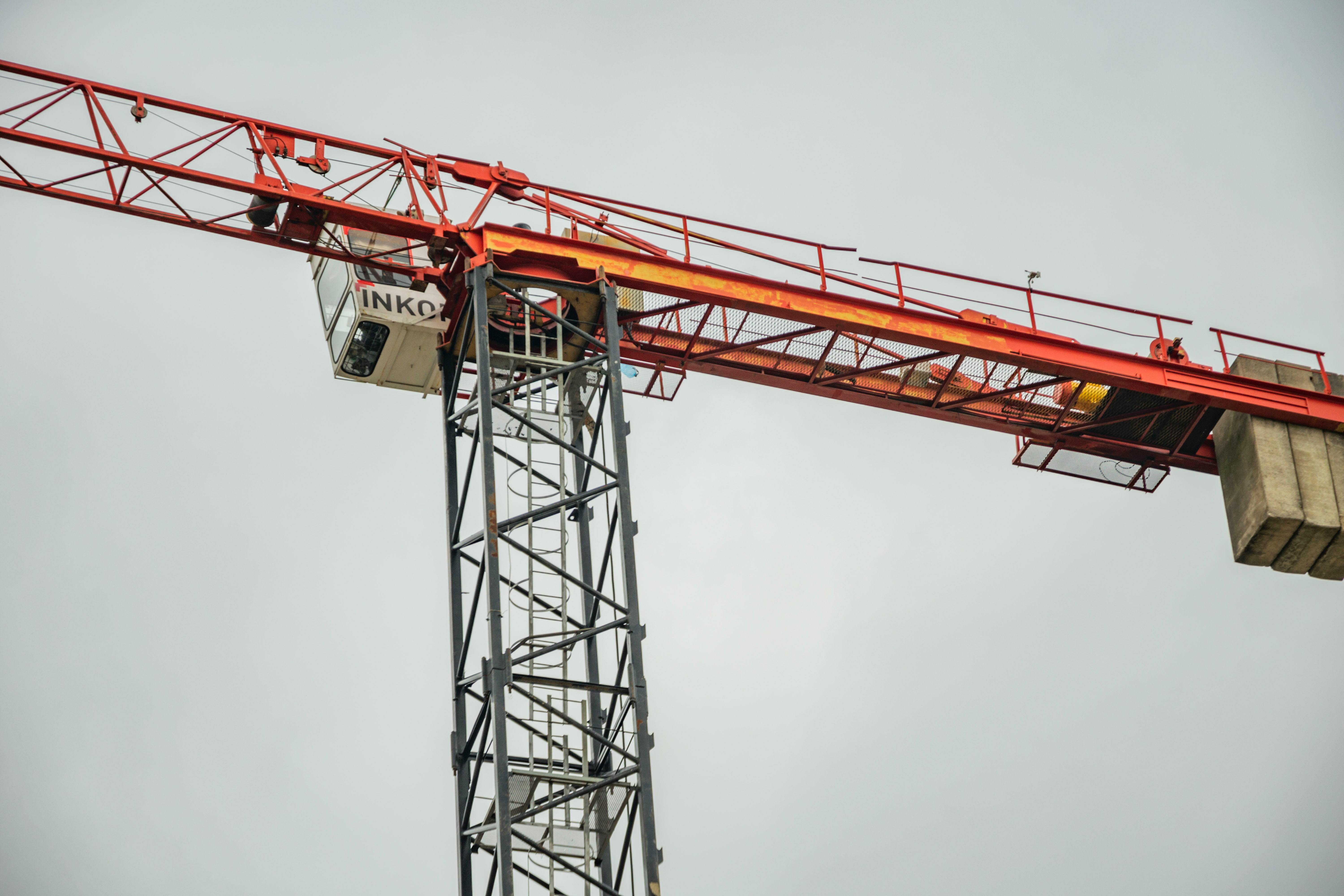 Grayscale Photo of a Tower Crane Under Cloudy Sky · Free