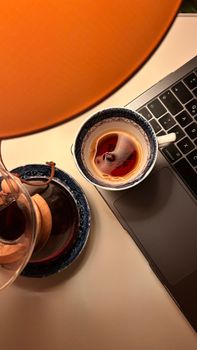 A warm, inviting workspace featuring a ceramic cup of tea and a laptop under soft lighting.