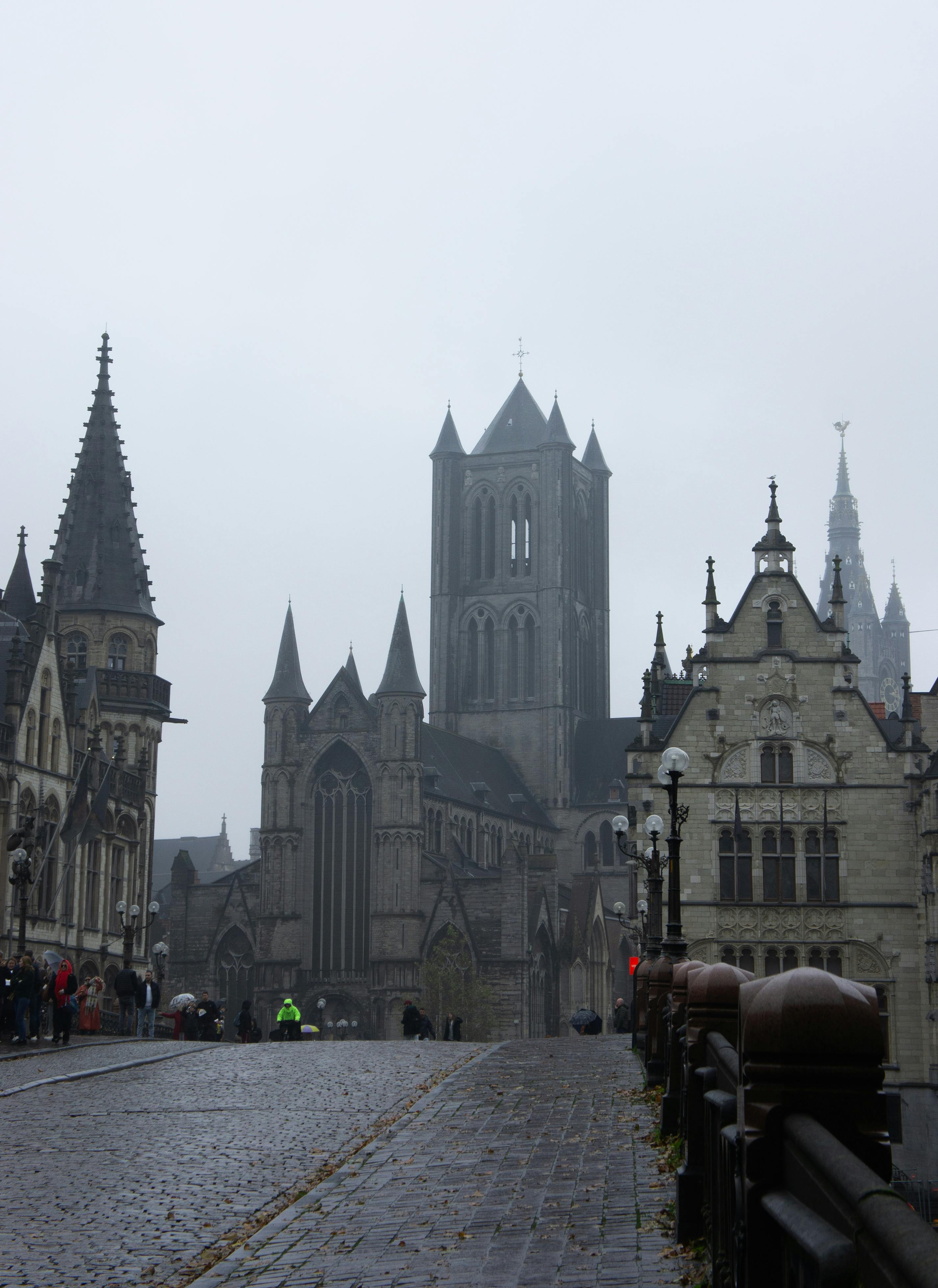 Majestic Gothic church facade in Ghent, framed by medieval buildings on a cobbled street.