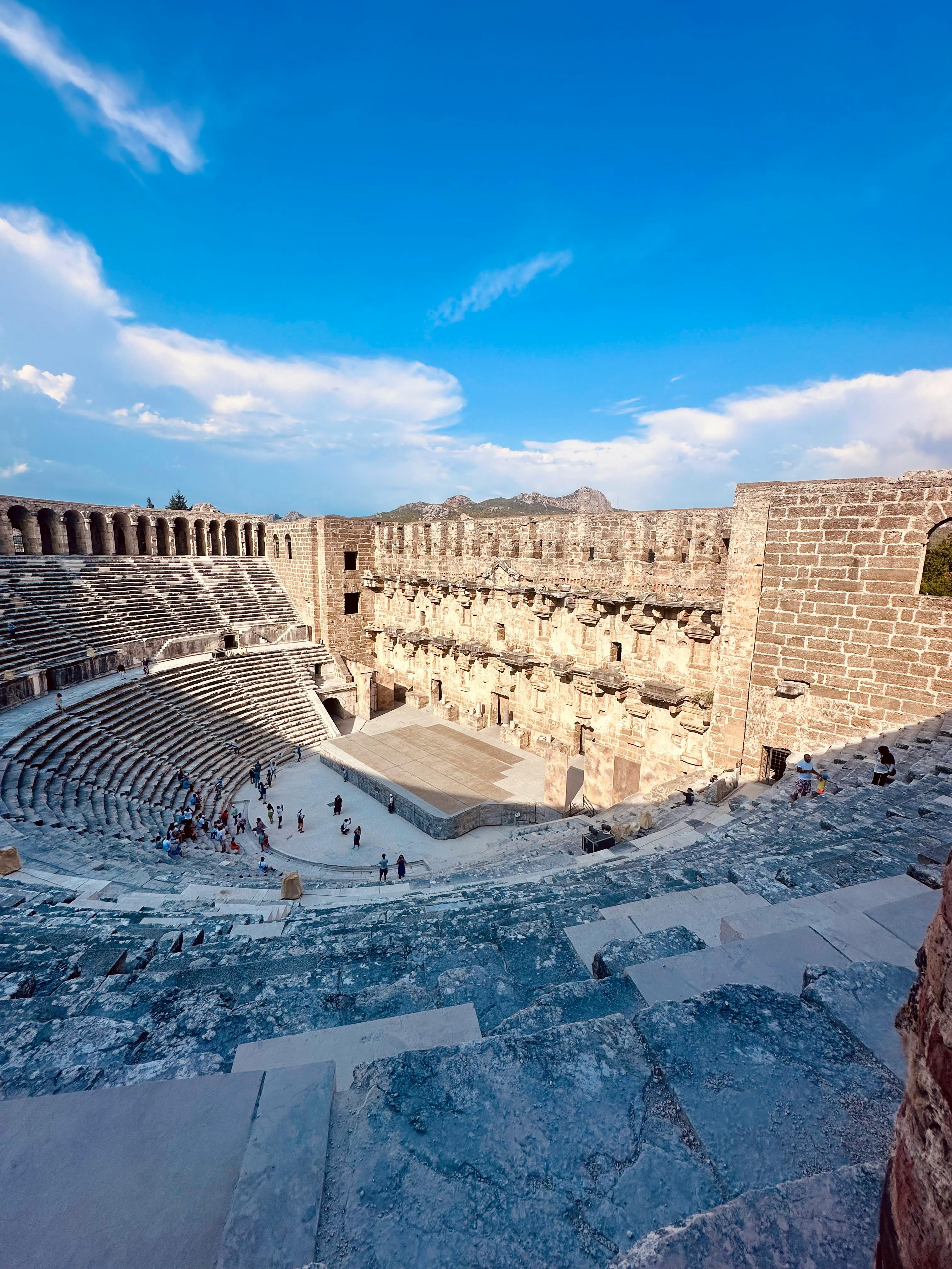 Free Stunning view of an ancient Roman amphitheater with stone architecture under a clear blue sky. Stock Photo