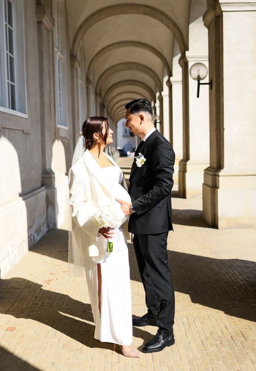 Free Stylish wedding couple sharing an intimate moment in a sunlit corridor. Stock Photo