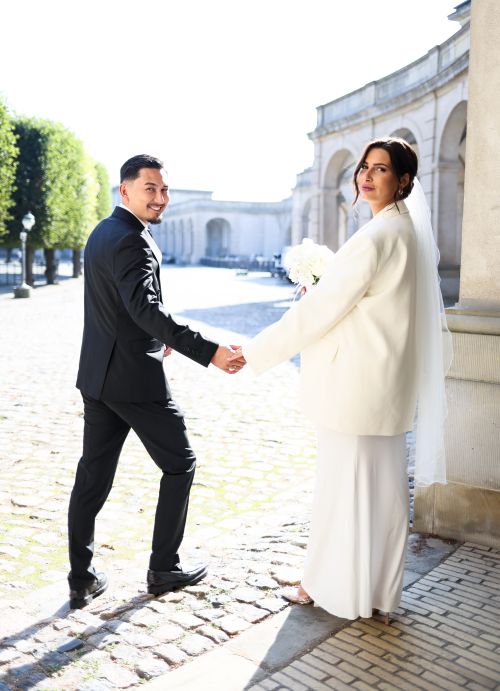 Free A bride and groom hold hands in a beautiful outdoor setting, exuding elegance. Stock Photo