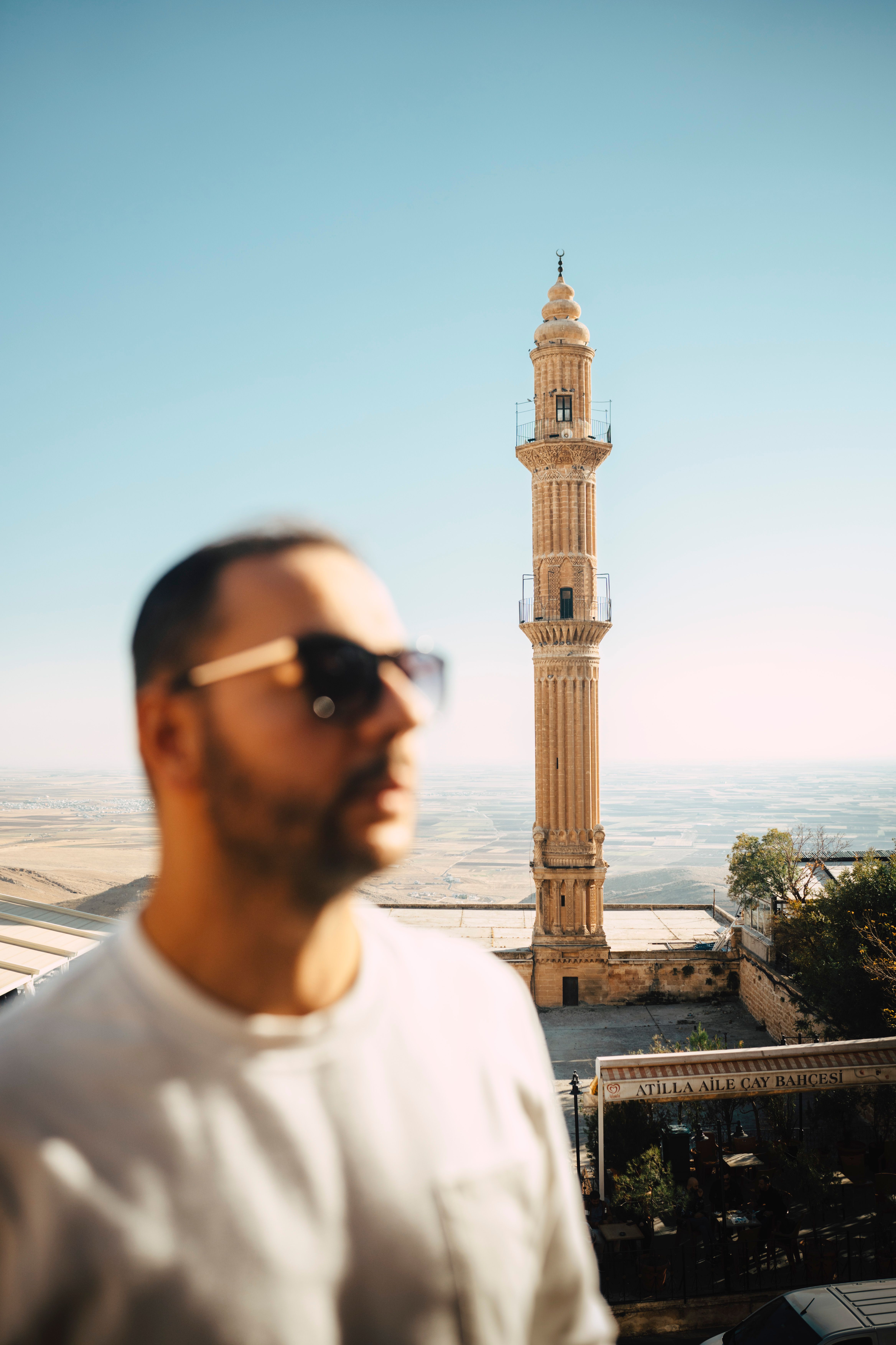 A man enjoying a sunny day with a historic minaret in Mardin city, Turkey.