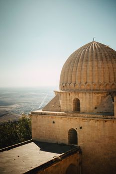 A beautiful architectural dome on a building in Mardin, Türkiye, with a scenic landscape view.