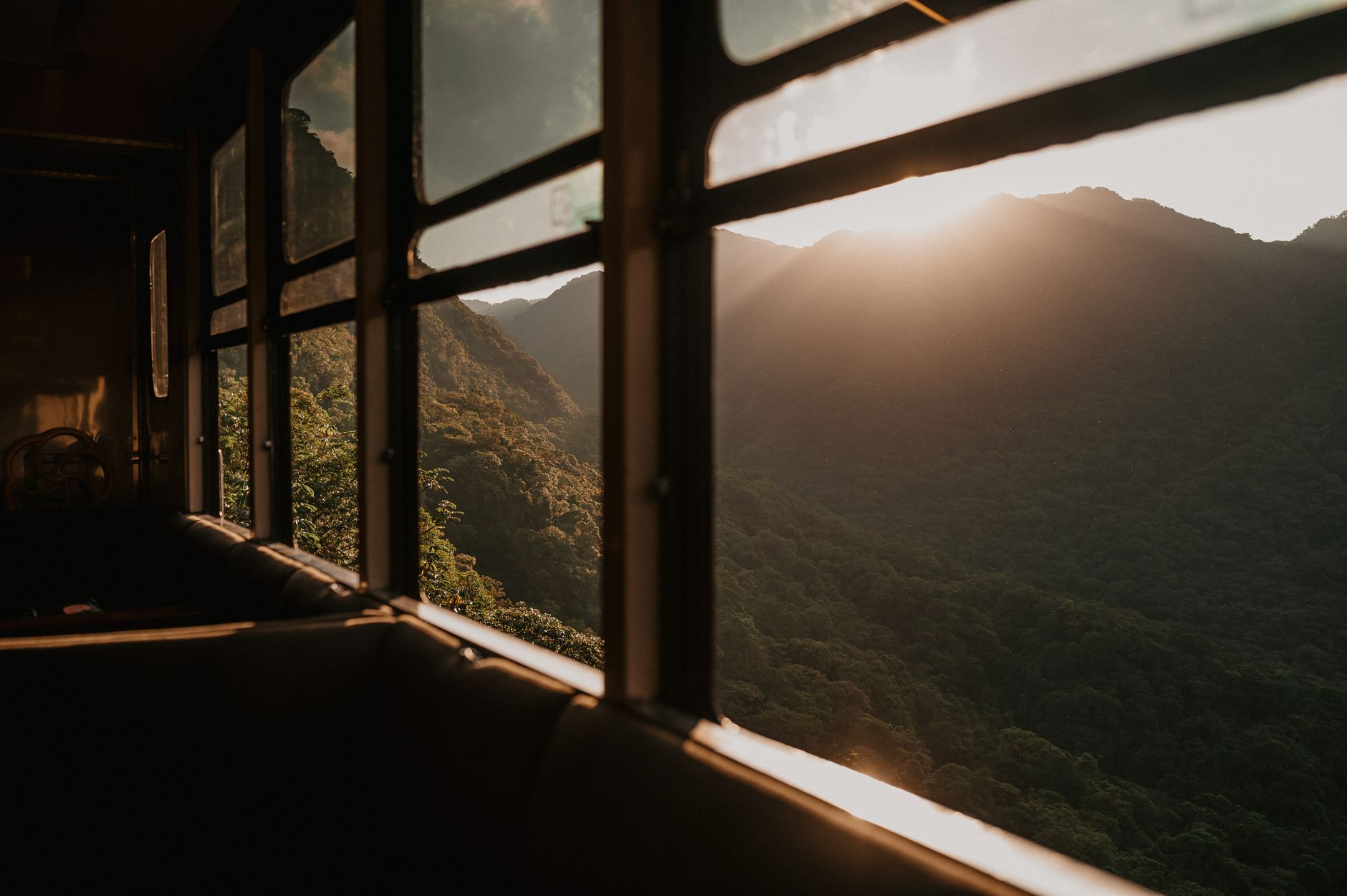 A refined interior view of a luxury train carriage with a panoramic mountain landscape visible through the window.