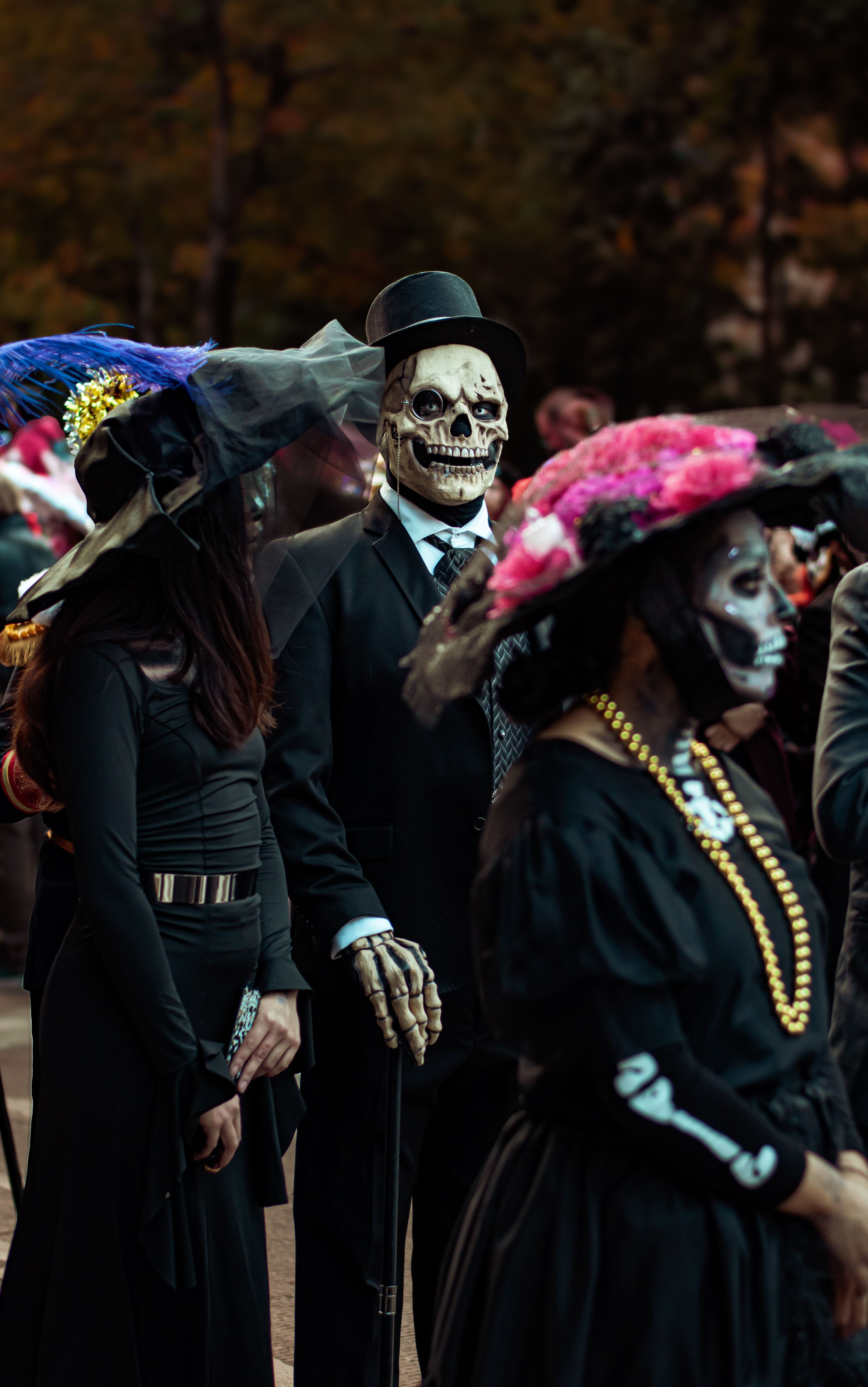 Parade participants in bright Day of the Dead costumes and painted faces walking in a community celebration