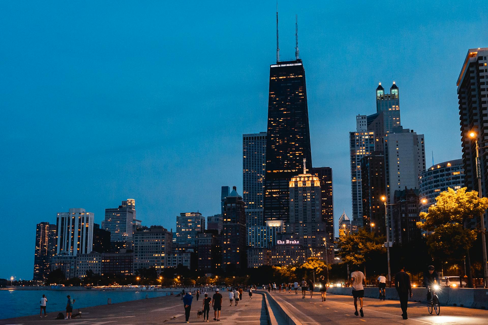 Evening view of Chicago's iconic skyline featuring the John Hancock Center and walking people.