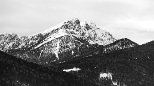 Free Monochrome view of a majestic snow-covered mountain peak surrounded by forested hills. Stock Photo