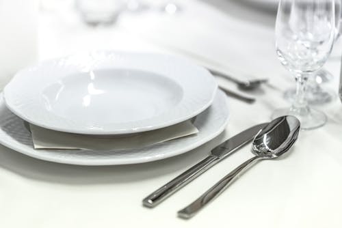 Mangkok Keramik Putih Bulat Ditempatkan Di Atas Meja Disamping Gelas Anggur