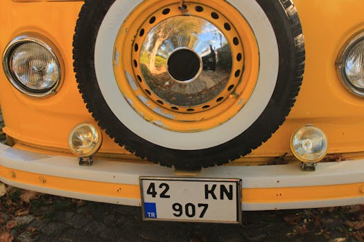 Close-up of a vintage yellow van with retro headlights and a spare tire.