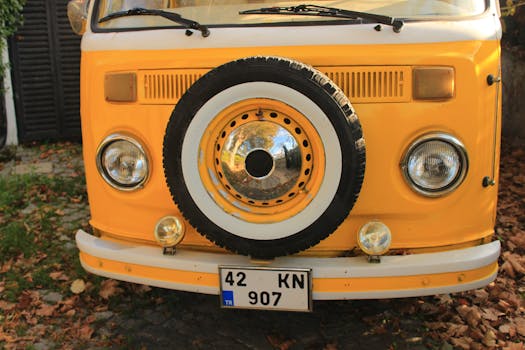 Close-up of a vintage yellow camper van with a decorative spare tire.