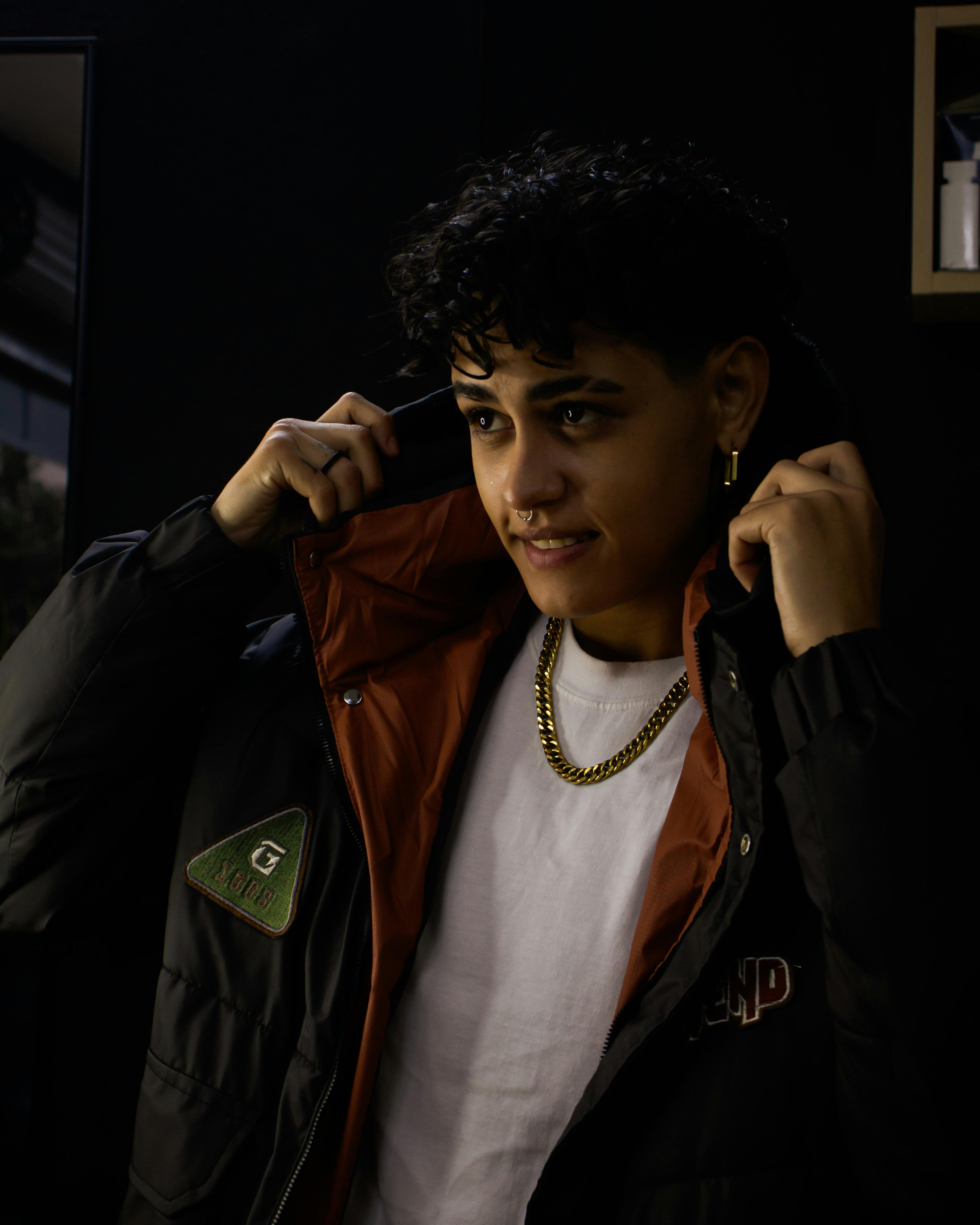 Gratis Un adulto alla moda indossa una giacca invernale con cappuccio, il cui look è esaltato da una luce soffusa. Foto a disposizione